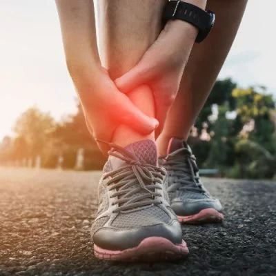A person is holding their ankle in pain while running.
