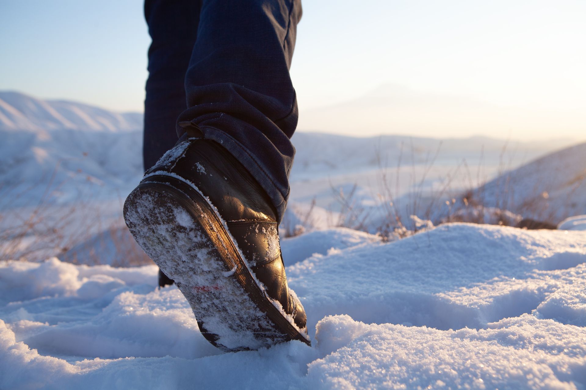 A person is walking in the snow wearing boots.