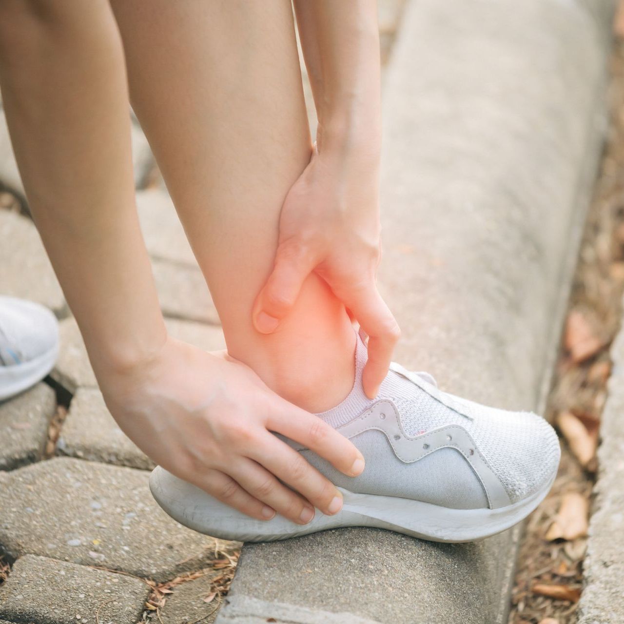 A person is holding their ankle in pain while running.
