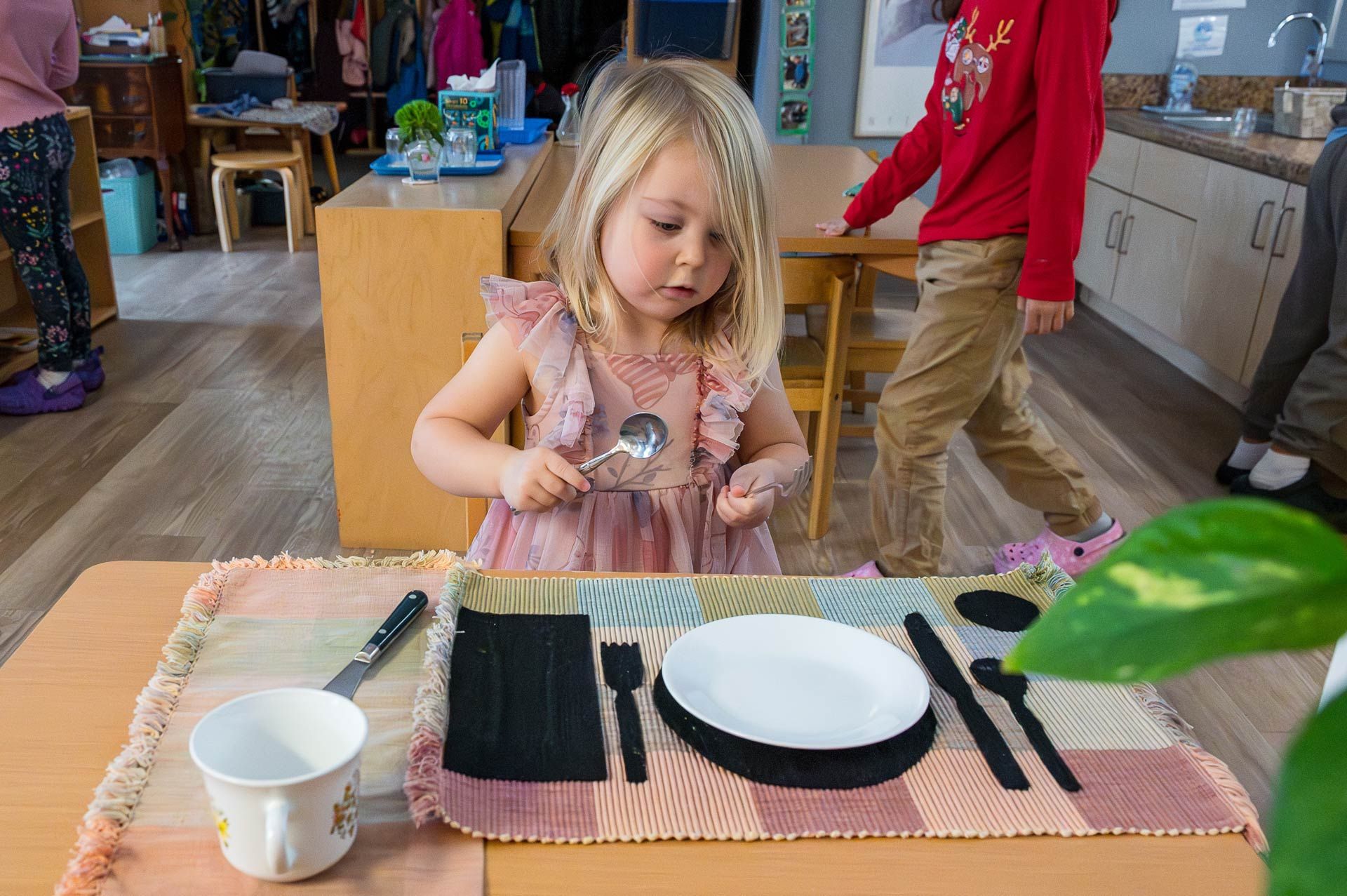 Montessori child practicing table setting activity in classroom
