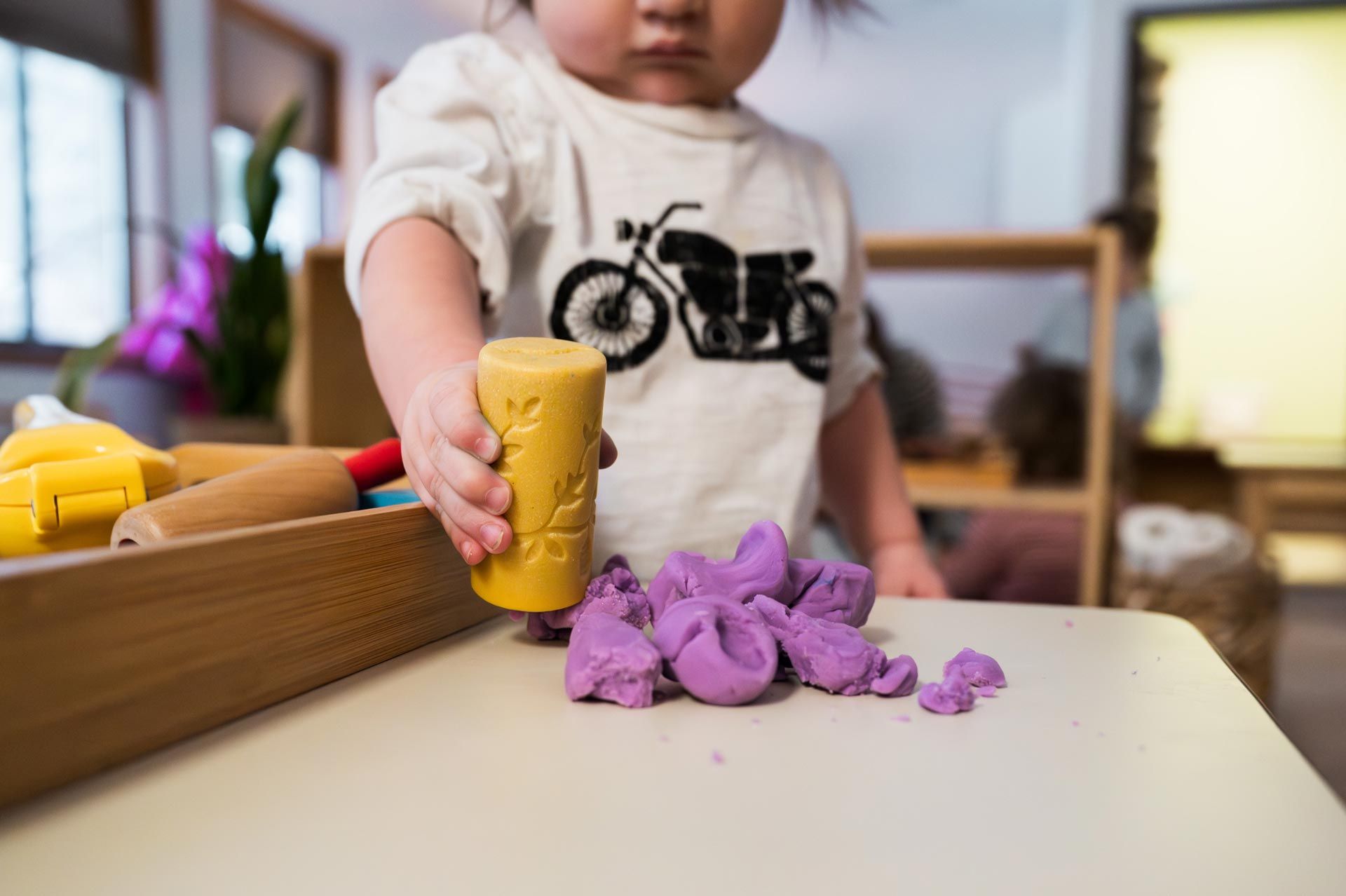 montessori child exploring modeling clay with stamp tool