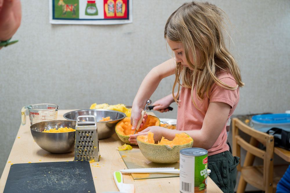 montessori child preparing food at a table with kitchen tools and ingredients