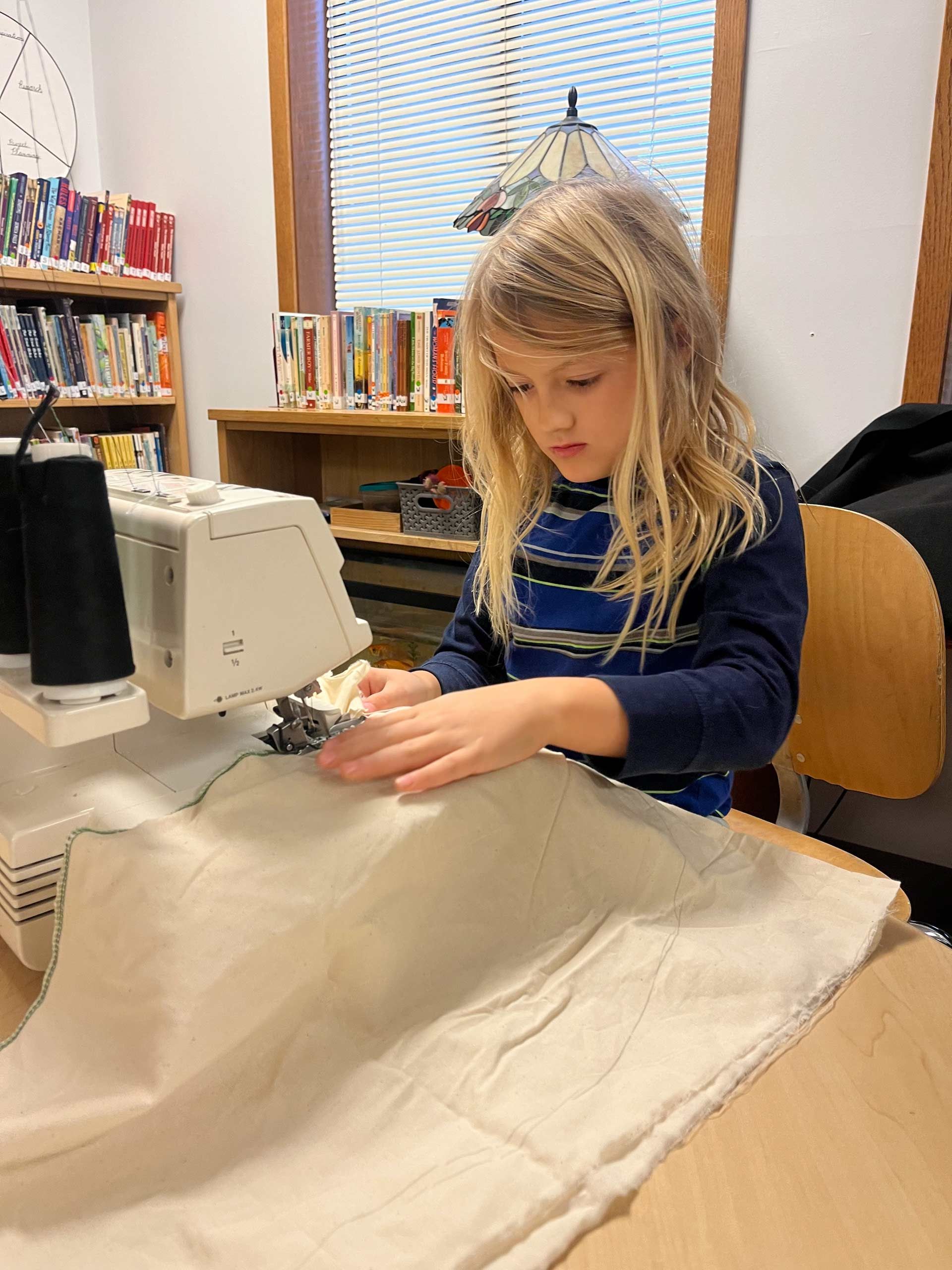 montessori child using sewing machine at wooden table