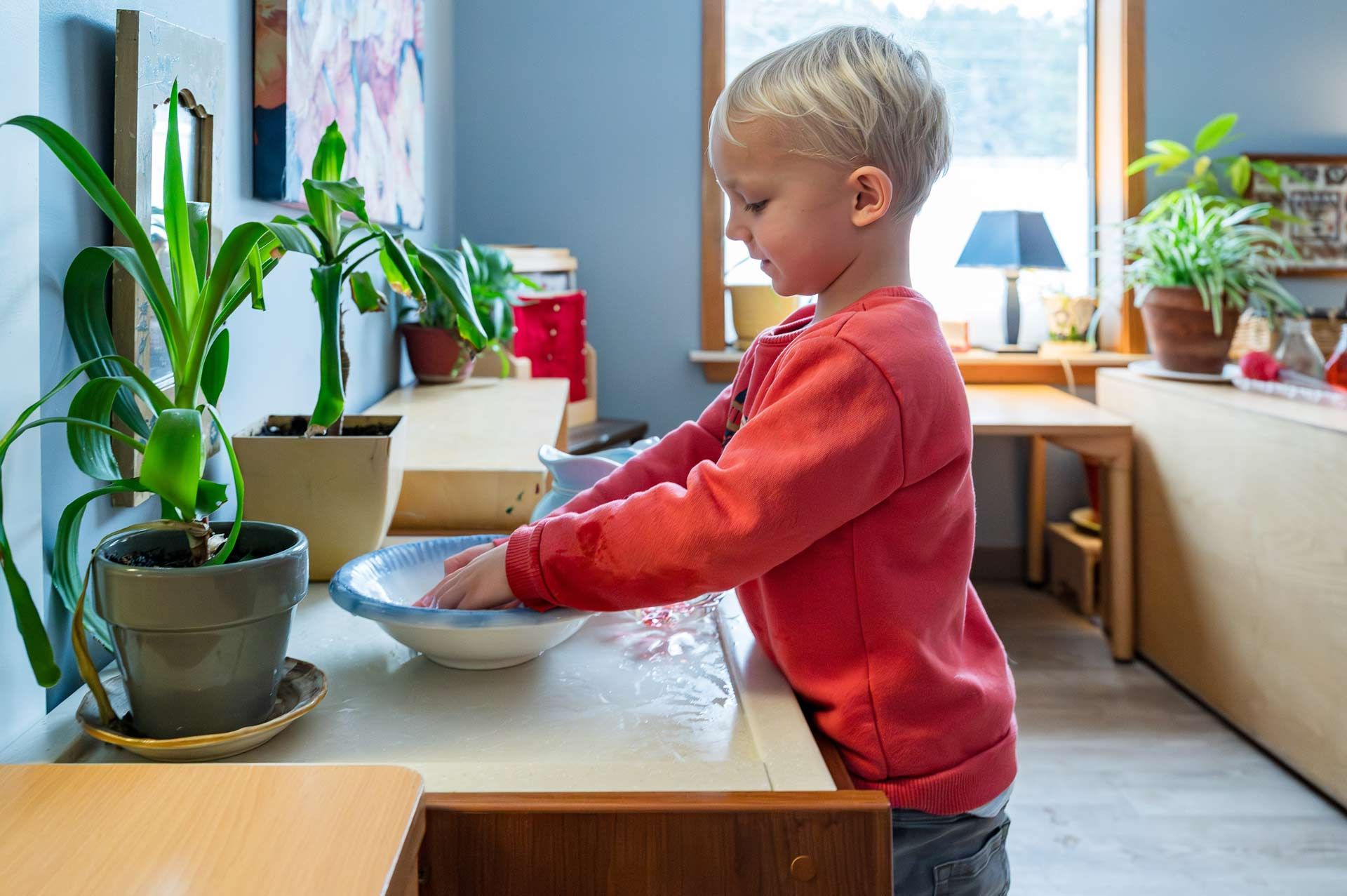 montessori child washing hands at a classroom work table