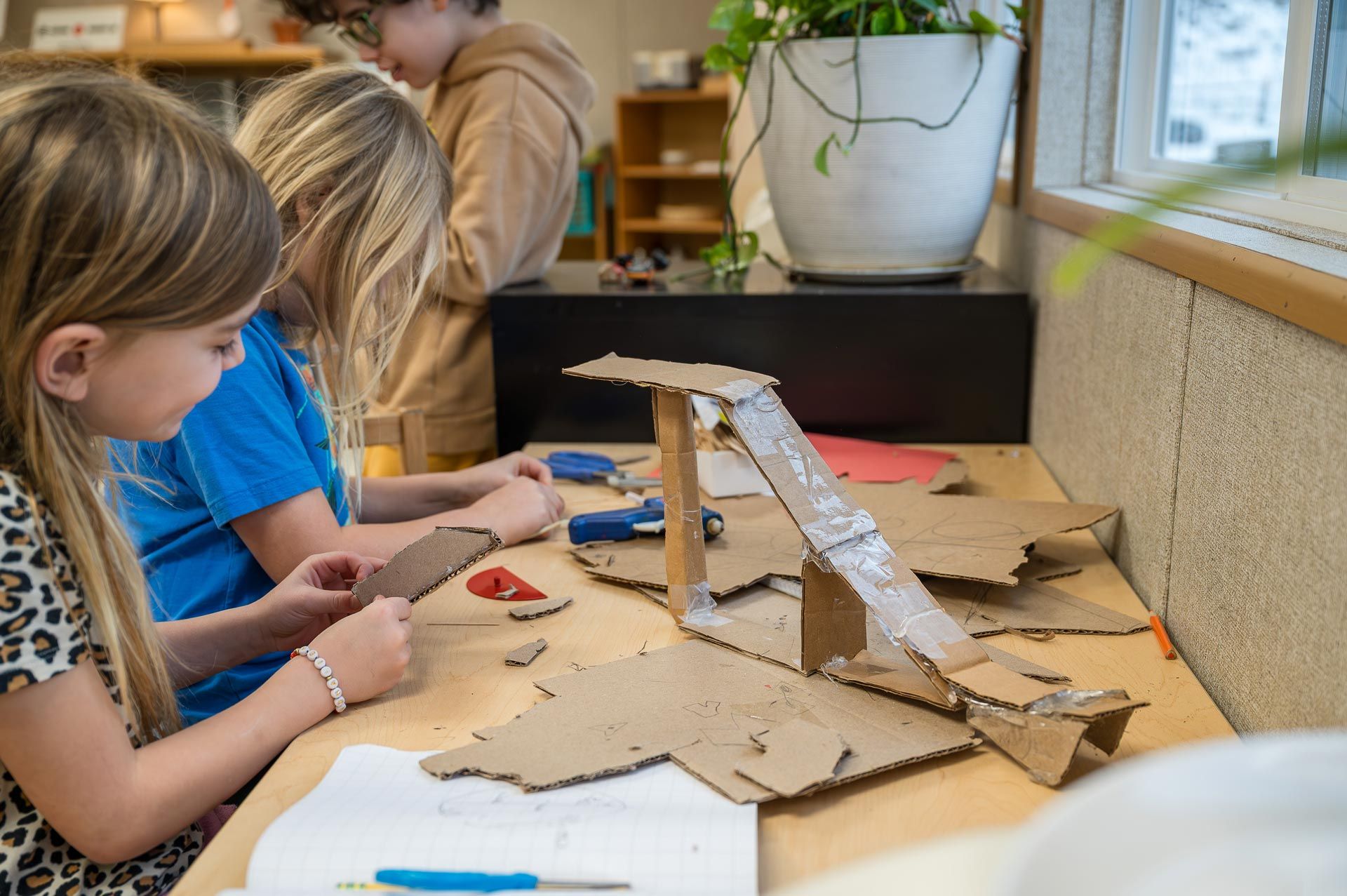 montessori children building a cardboard ramp together at a classroom table