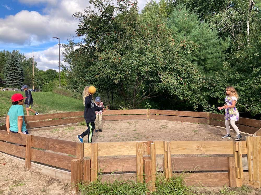 montessori children playing gaga ball in outdoor enclosure