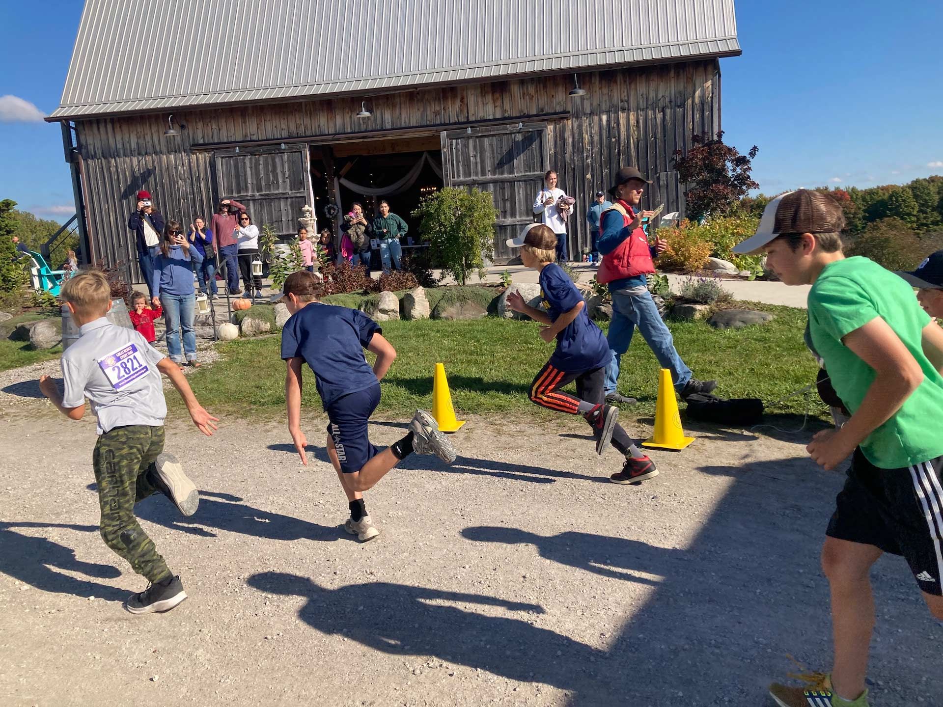 montessori children running race near barn during fall event