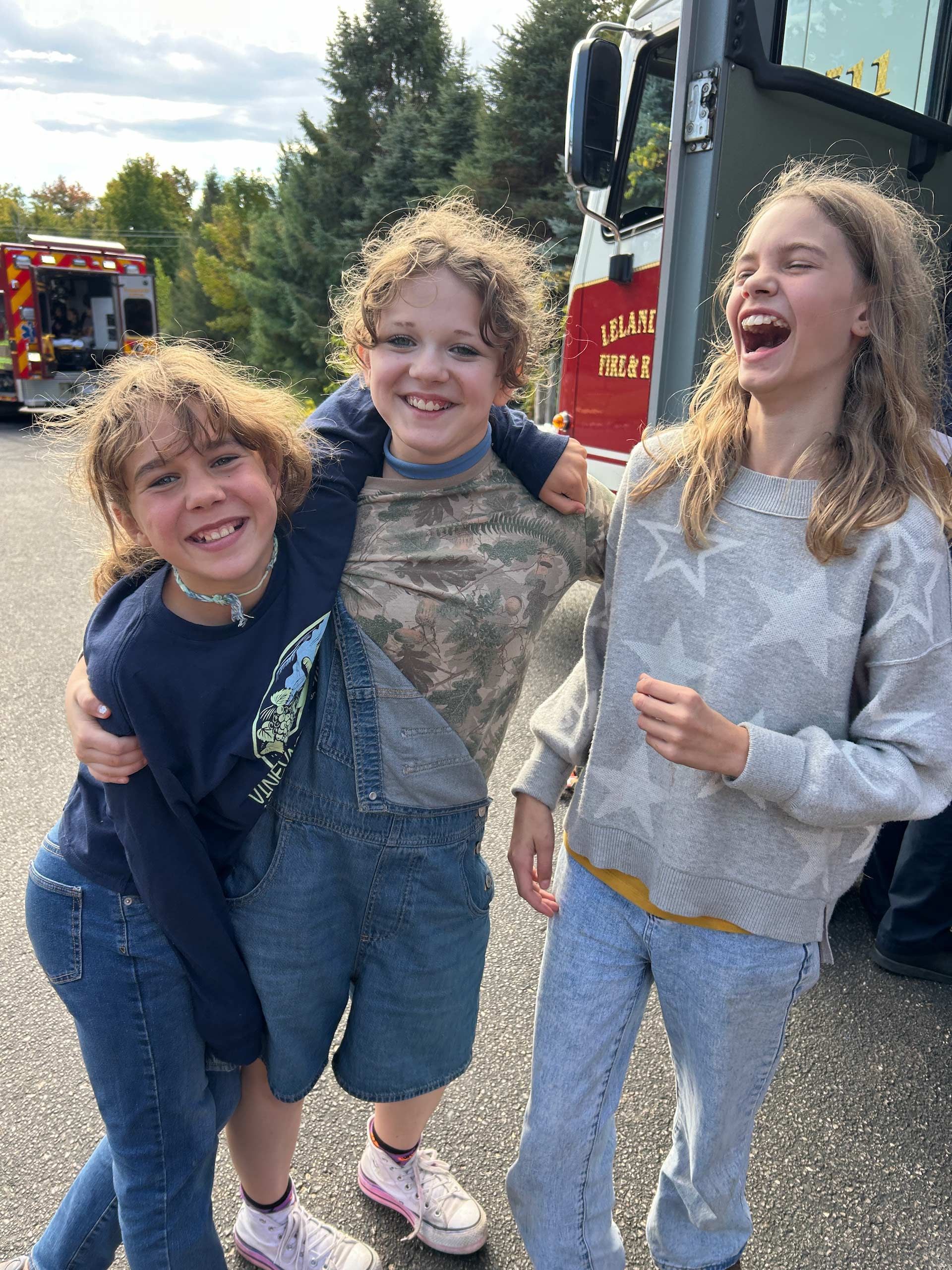 Montessori children smiling near a fire truck at a community event.