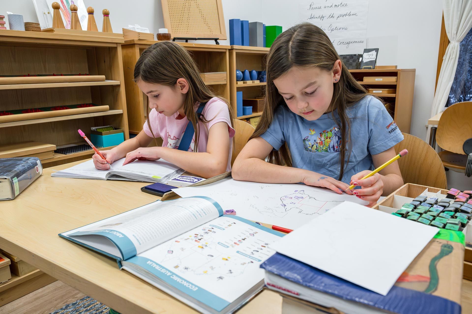 montessori children working with geography and economics materials at a classroom table