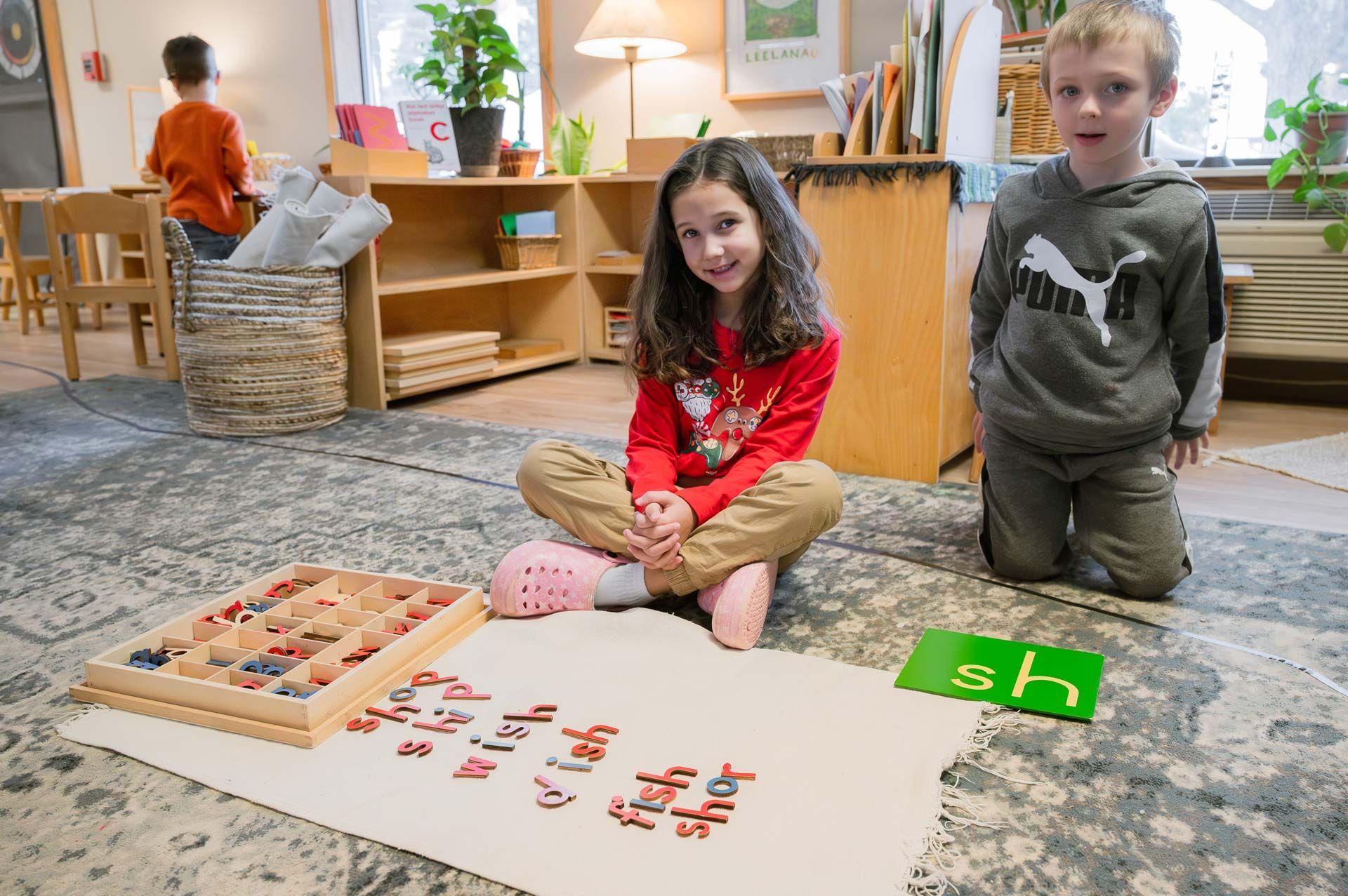 montessori children working with movable letters on a mat in a classroom setting