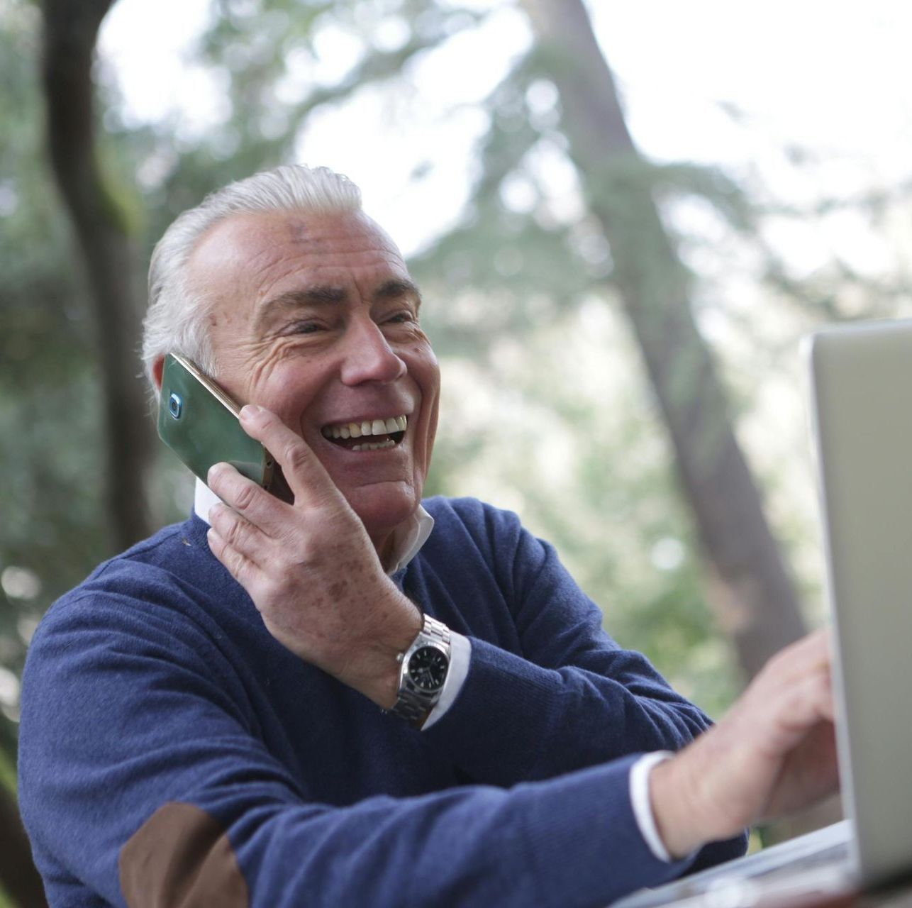 A man is smiling while talking on a cell phone
