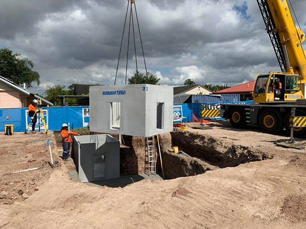 A crane is lifting a concrete box into a hole