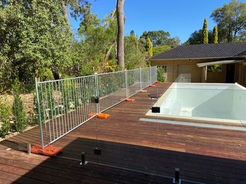 A fence around a swimming pool with a house in the background.