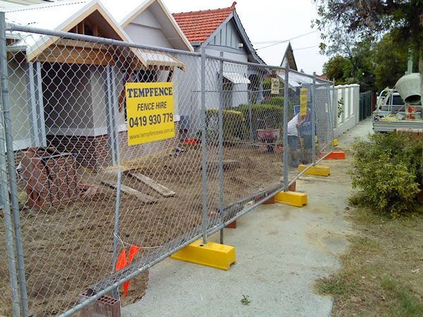 A chain link fence with a yellow sign that says temptence