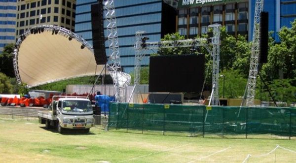A white truck is parked in a grassy field in front of a large building.