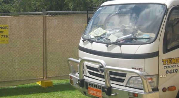 A white hino truck is parked in front of a fence