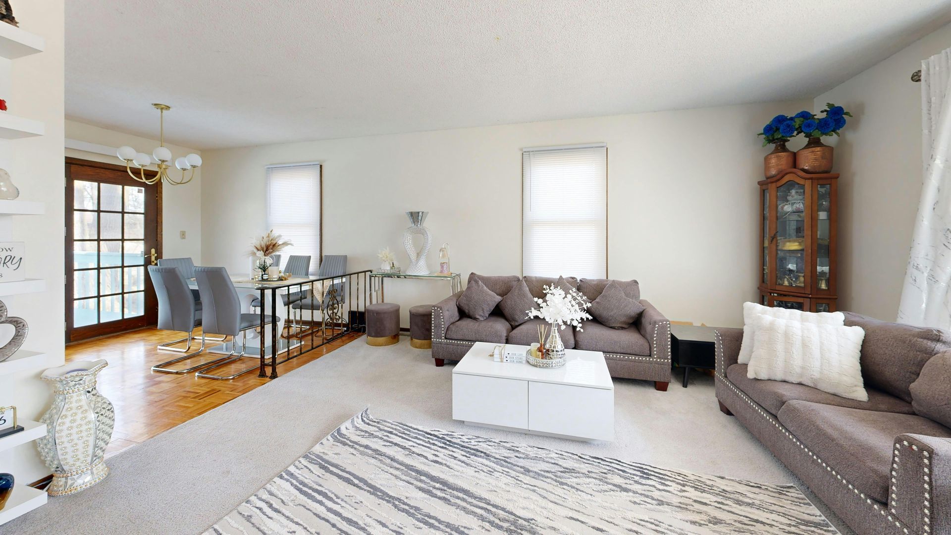Living room with gray sofas, white walls, rug, table, and a wooden door.