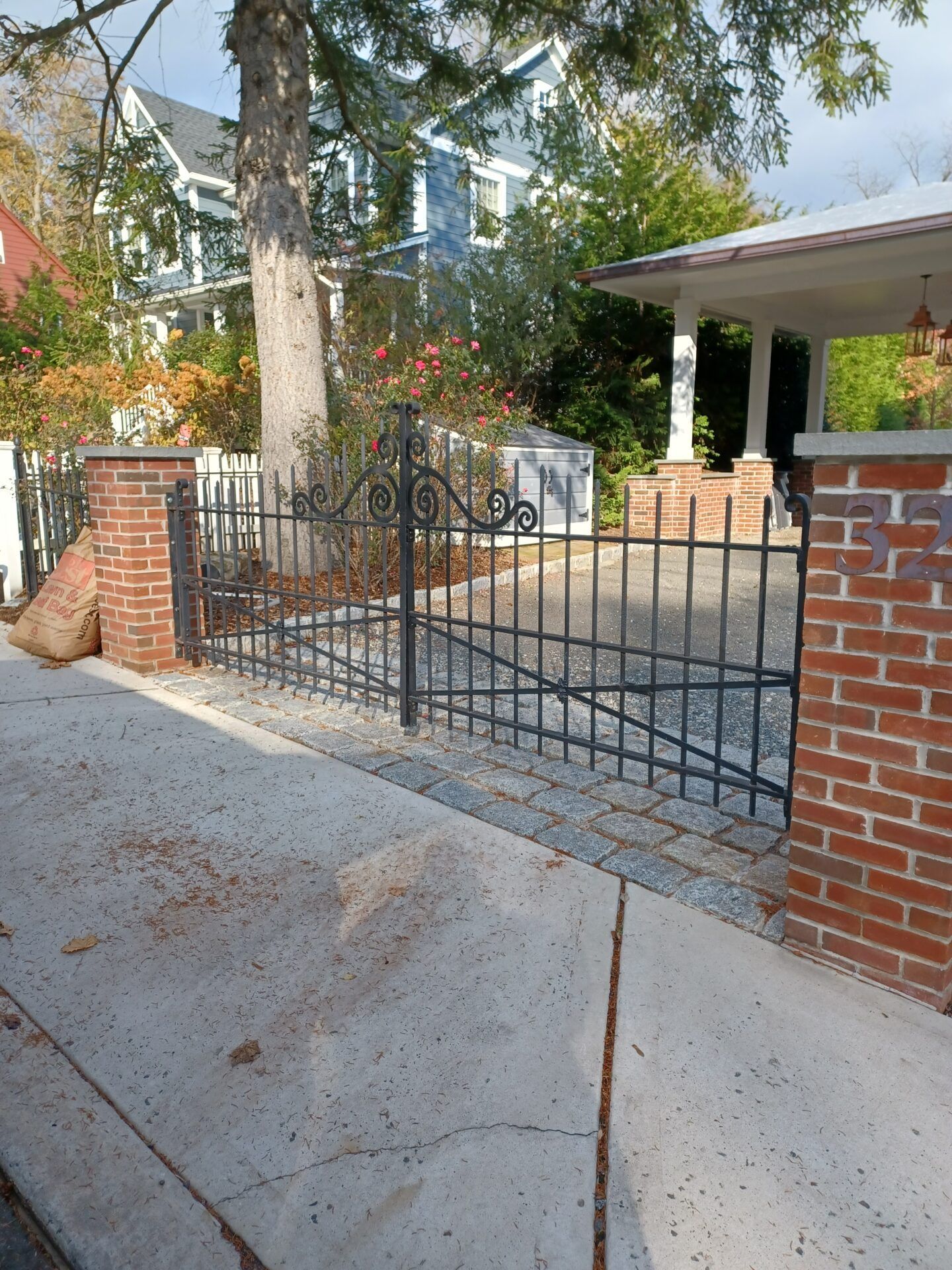 White railings surround a sunken concrete staircase leading down to double glass doors on the side of a shingled house.