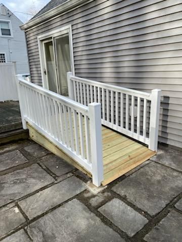 A white vinyl privacy fence runs across a grassy yard under a cloudy sky, with houses visible in the background.