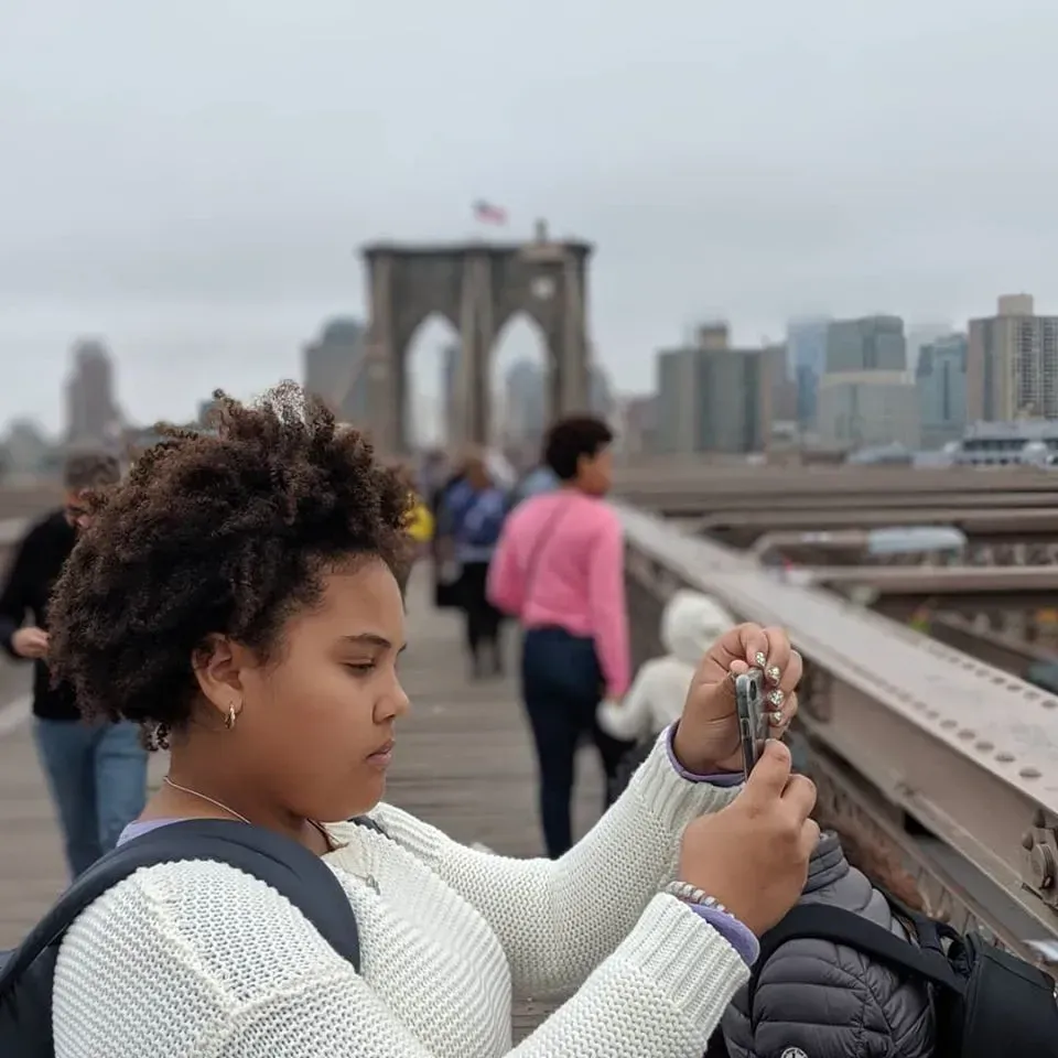 A woman is taking a picture of a bridge with a camera.