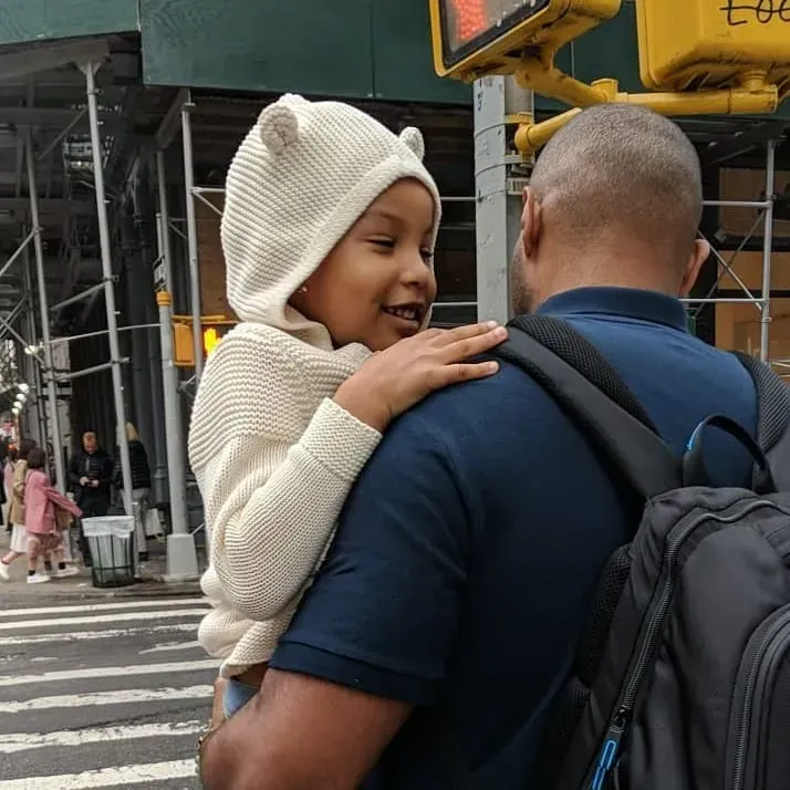 A man carrying a child wearing a bear hat