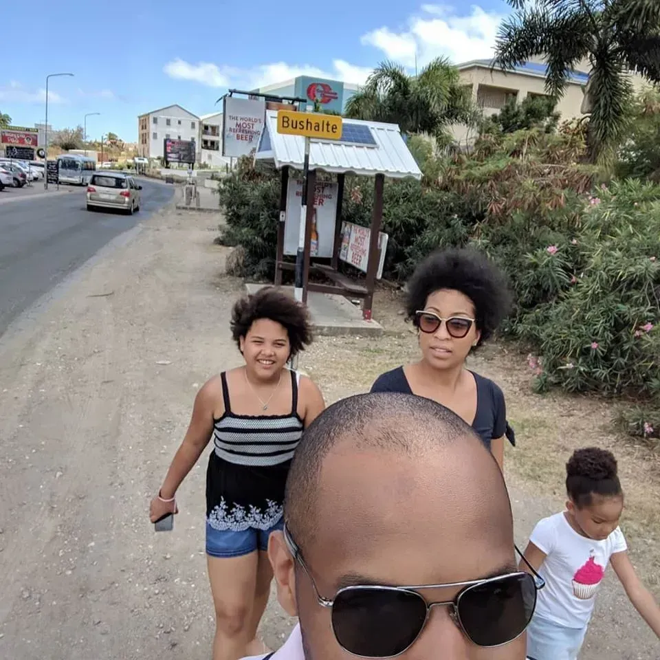 A group of people are walking down a street in front of a bus stop that says available