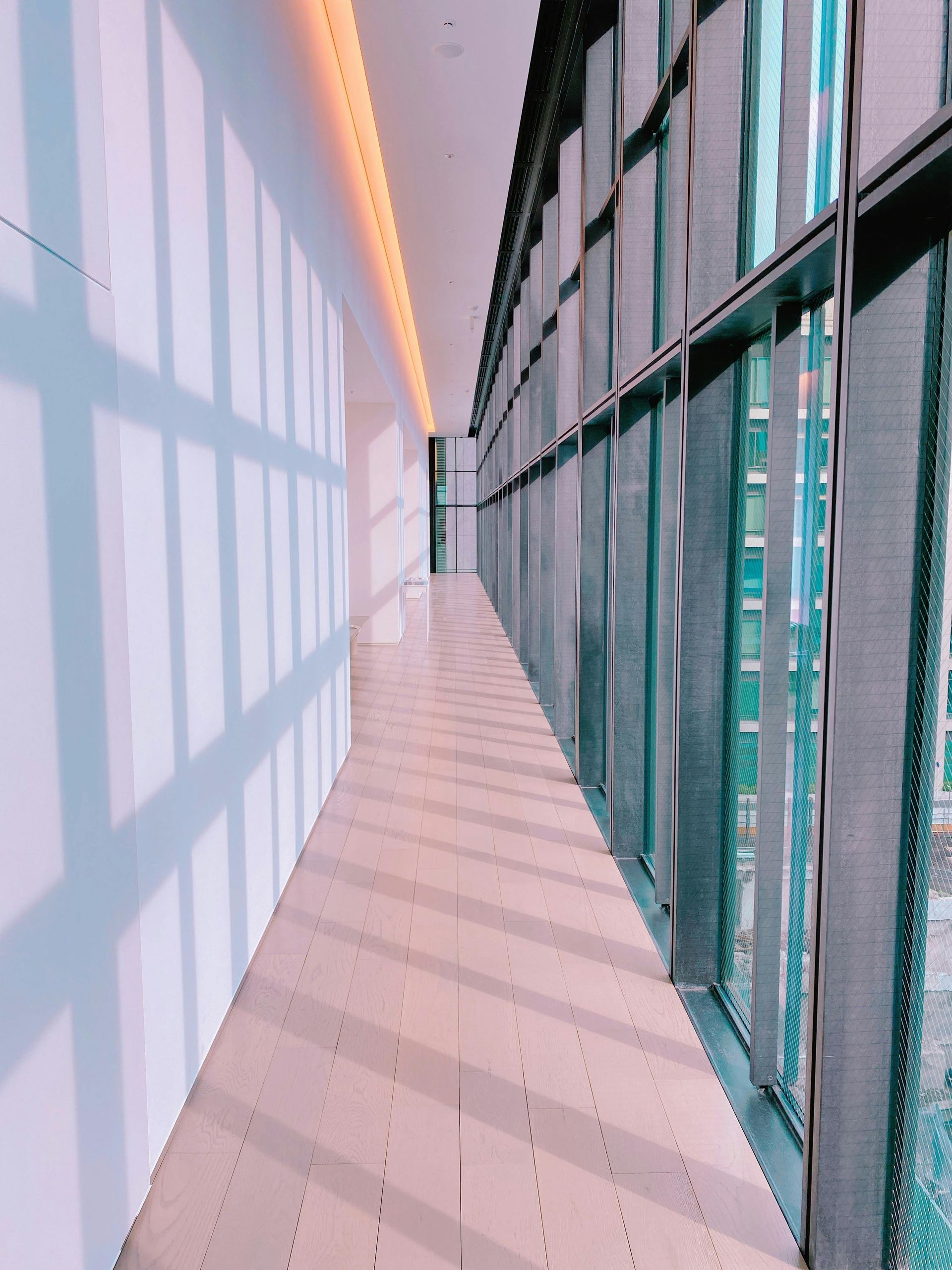 Cucina e sala da pranzo con pareti in mattoni a vista, tavolo bianco e sedie grigie. Finestre luminose e lampade a sospensione.