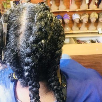 Woman with gray hair in two French braids, near a wig display.