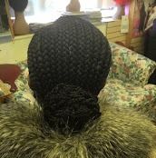 Braided hair bun, seen from the back, atop fur collar, indoor setting.