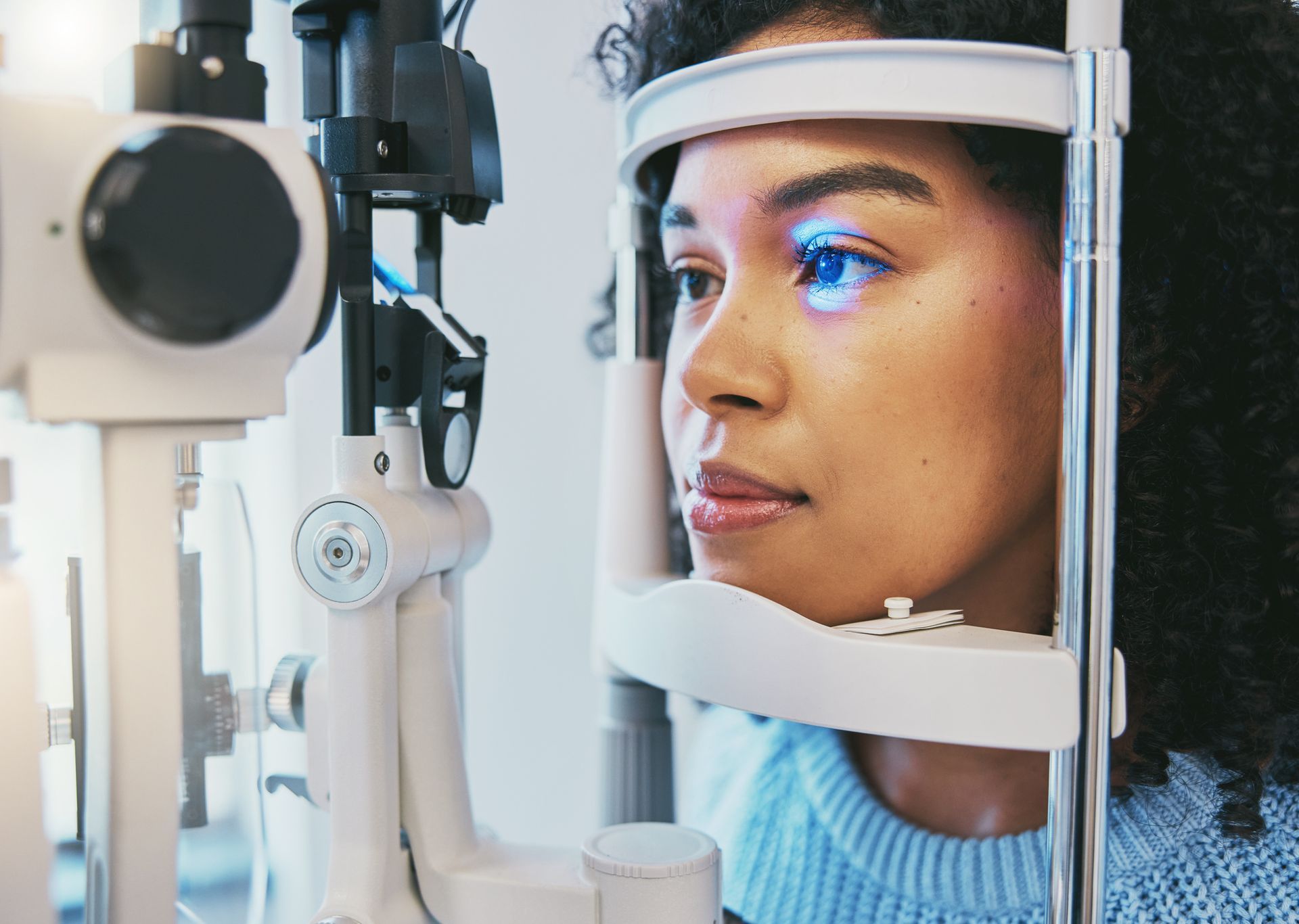 A woman is examining a man 's eye with a microscope