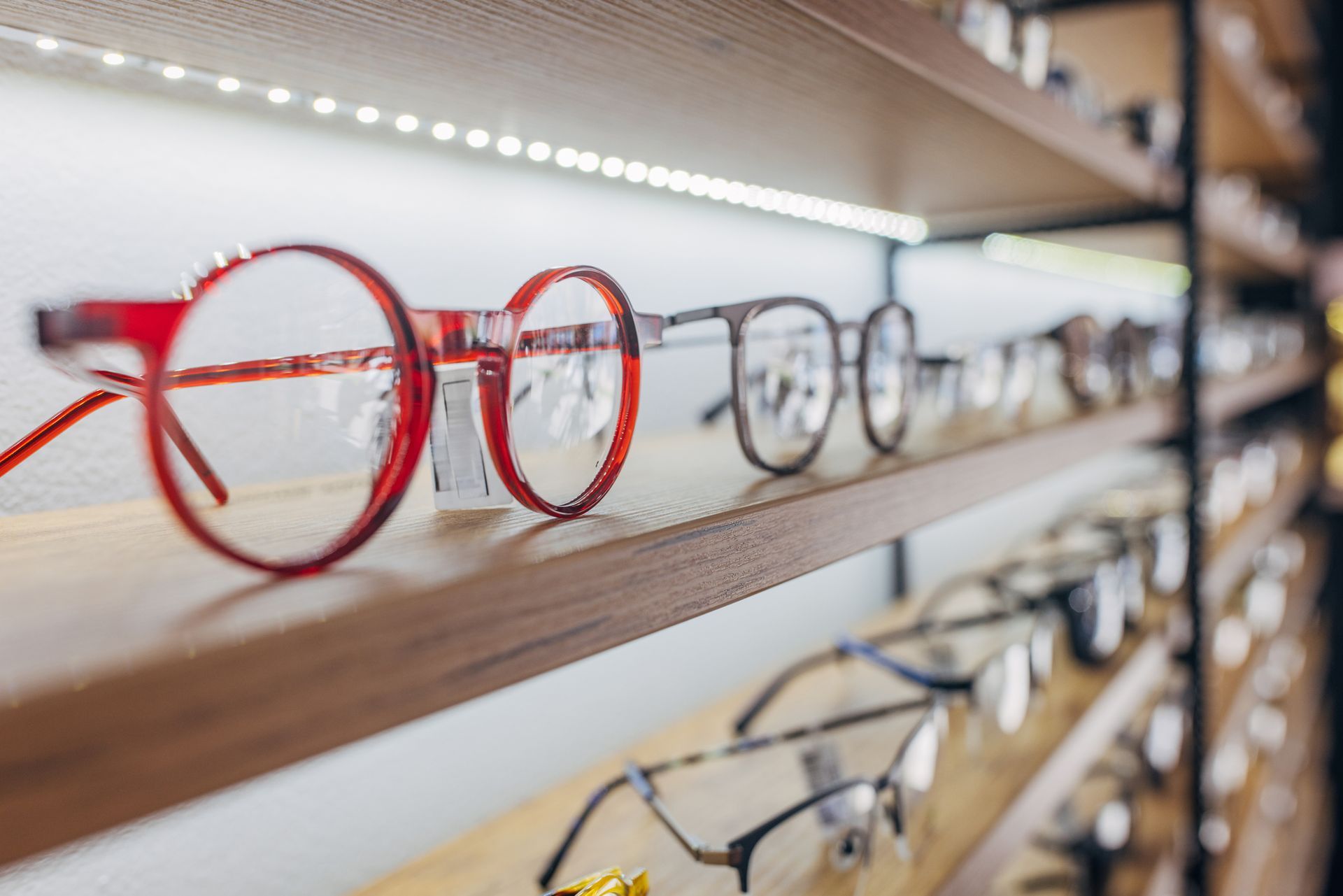 A row of glasses sitting on top of a wooden shelf.