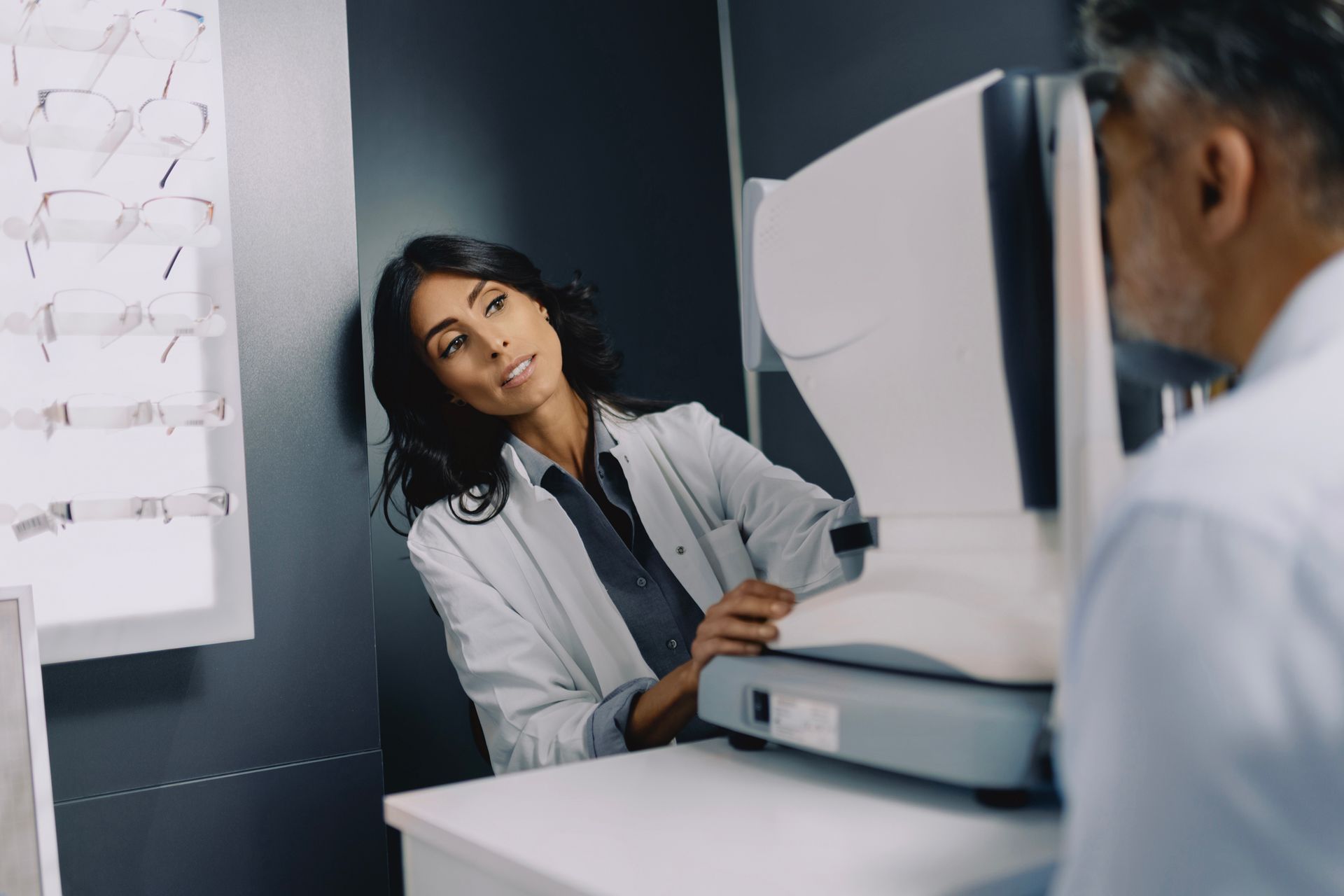 Female ophthalmologist performing diabetes eye assessments on senior male patient.