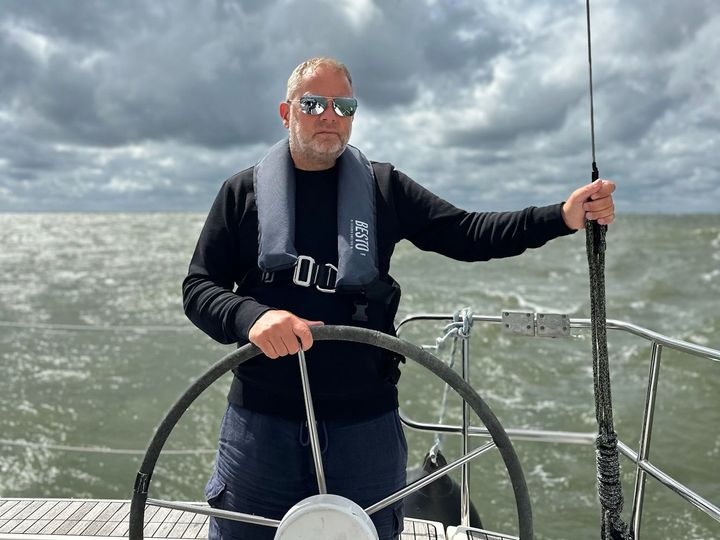 Mindset coach Marc Dijk bestuurt een boot op een ruige zee.