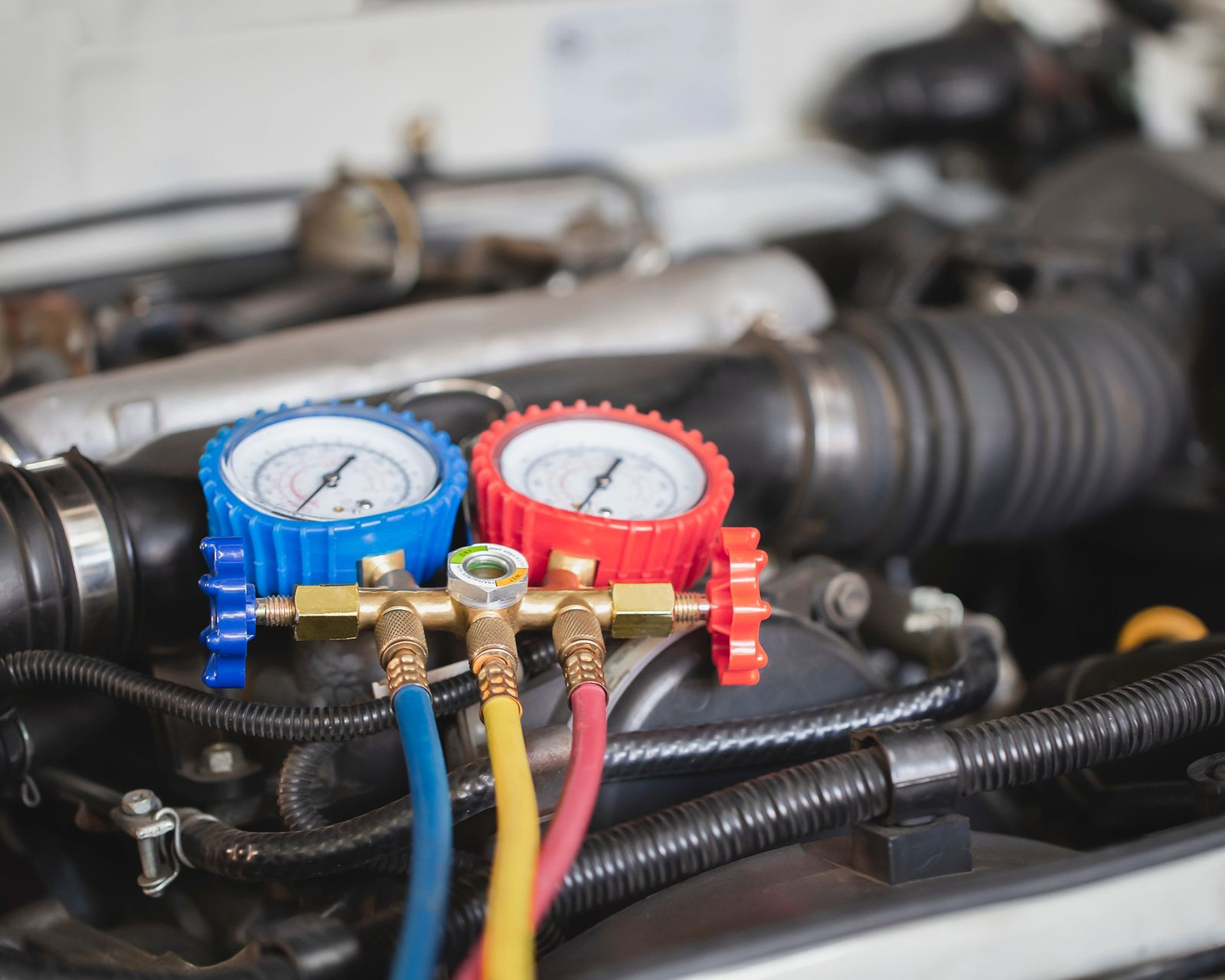 Persona que conecta una manguera azul a un colector de medición, probablemente para reparar el aire acondicionado.