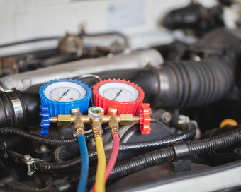 Persona que conecta una manguera azul a un colector de medición, probablemente para reparar el aire acondicionado.