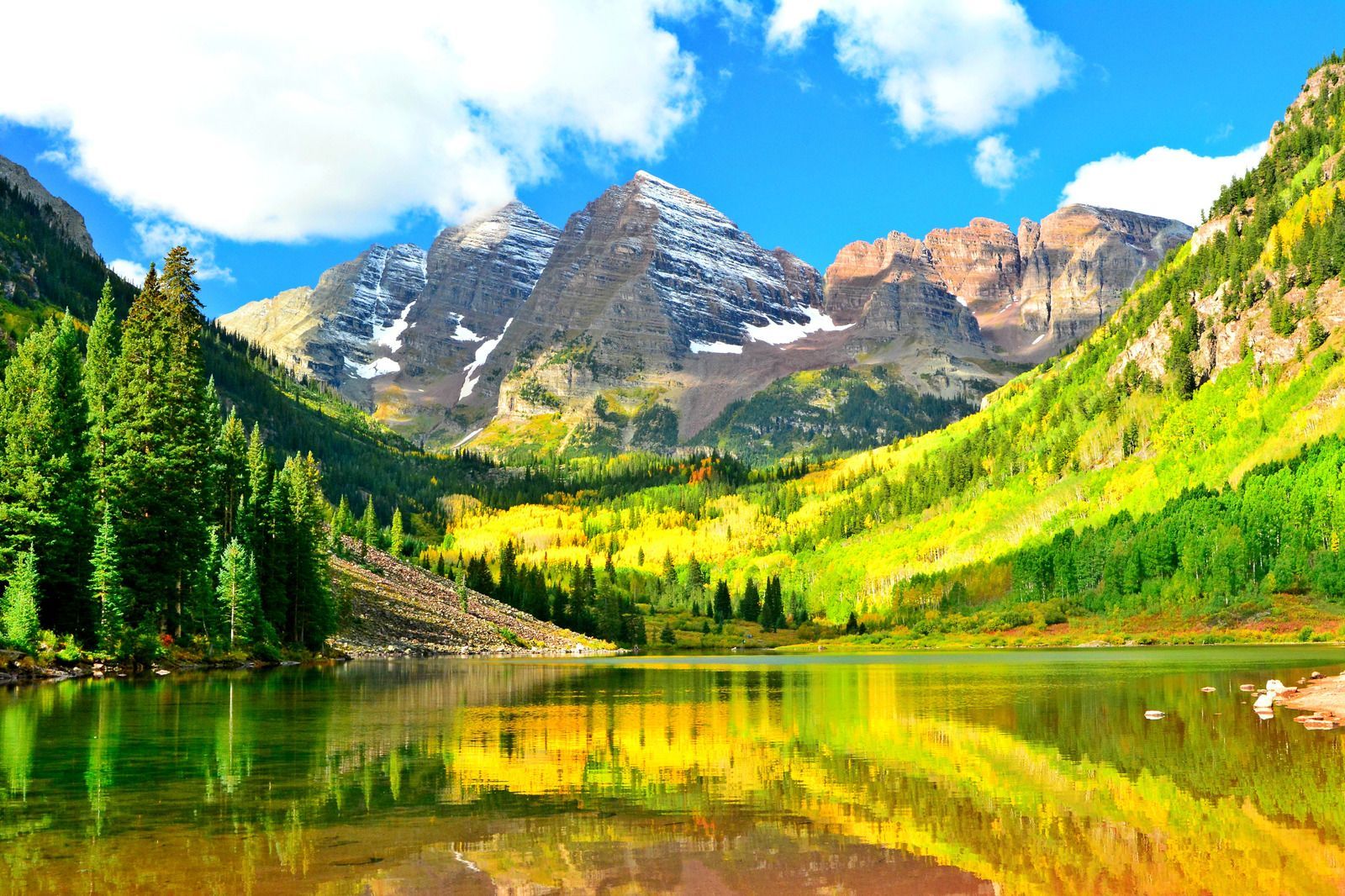 A lake surrounded by mountains and trees on a sunny day
