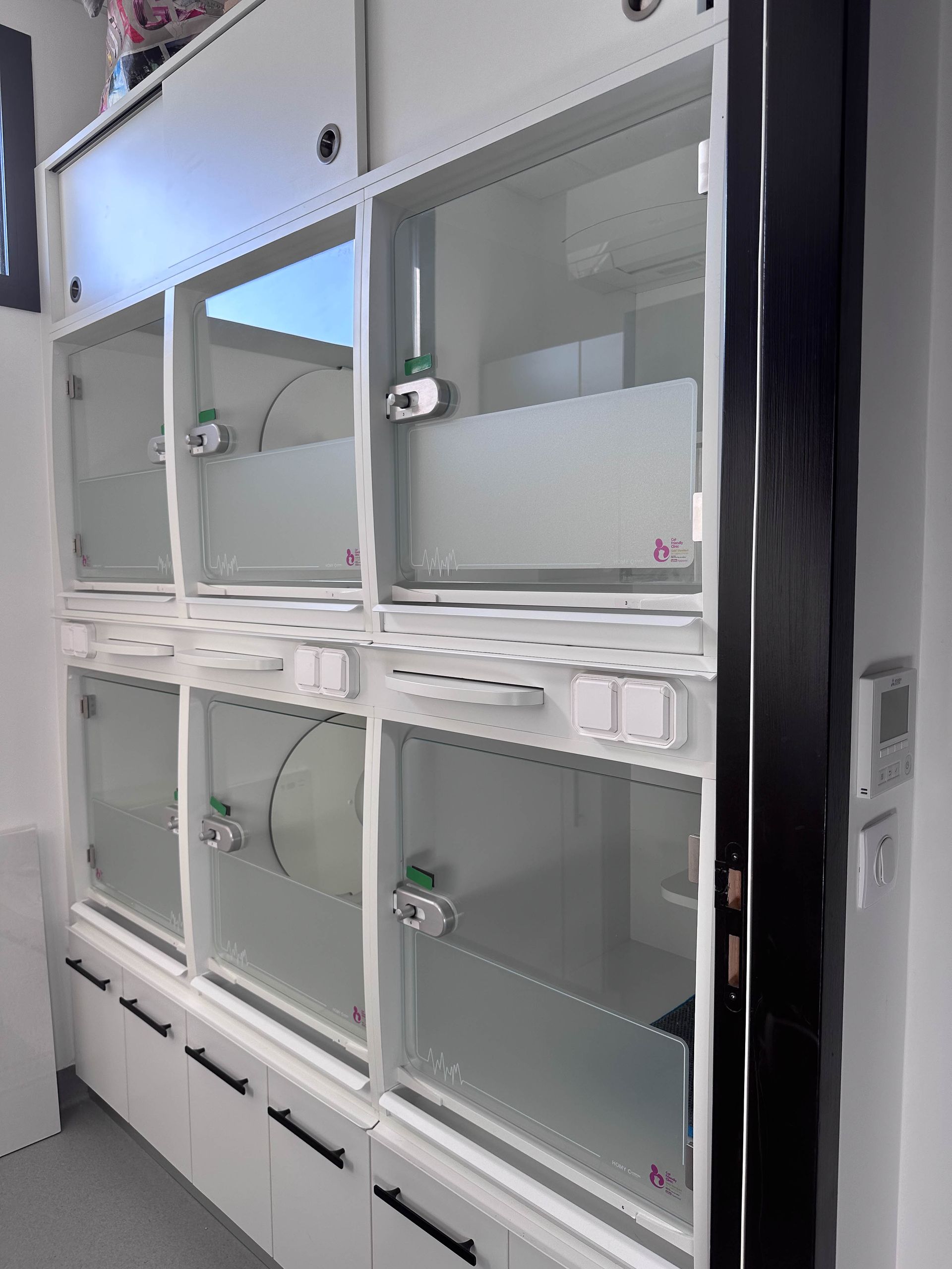 Des cages blanches pour animaux, avec des portes vitrées, sont empilées dans une clinique.