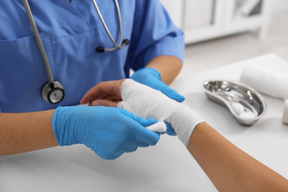 Healthcare worker wrapping a patient’s hand with a white bandage in a clinic