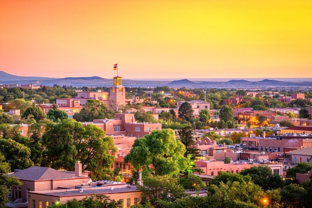 Adobe buildings and trees bathed in orange and yellow sunset light; Santa Fe, New Mexico.