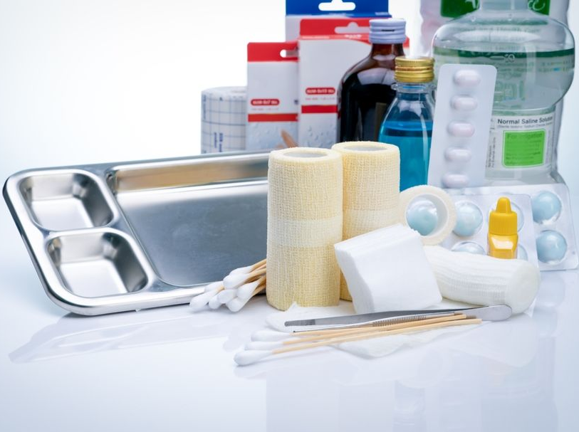 Medical supplies, including bandages, swabs, and bottles, arranged on a reflective surface.