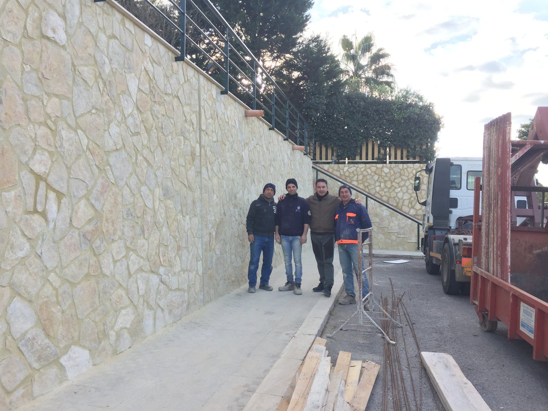 Quattro uomini di fronte ad un muro costruito in pietra