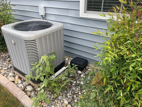 an air conditioner is sitting on the side of a house next to a window with a bug bait box
