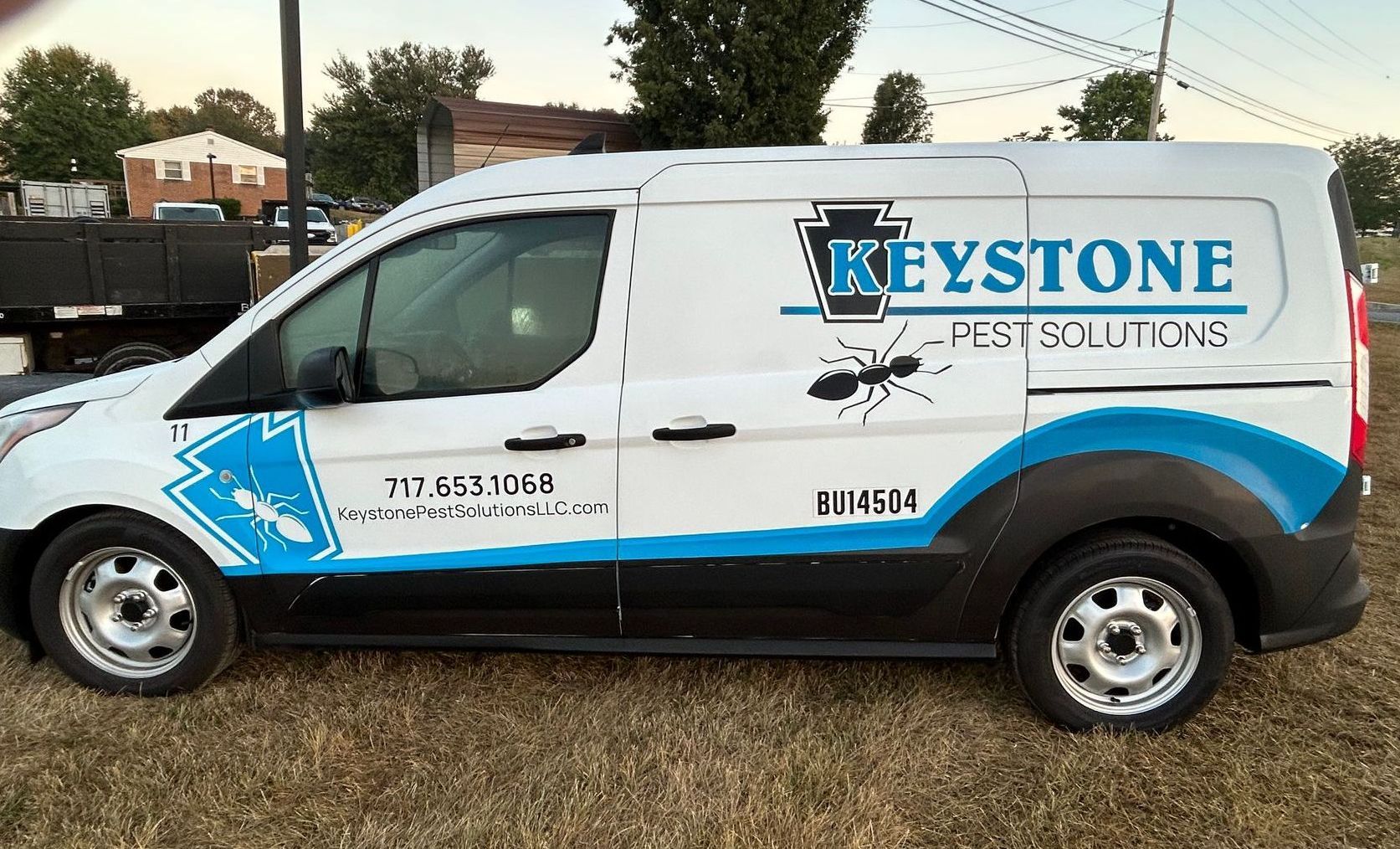 a keystone pest solutions van is parked in a field