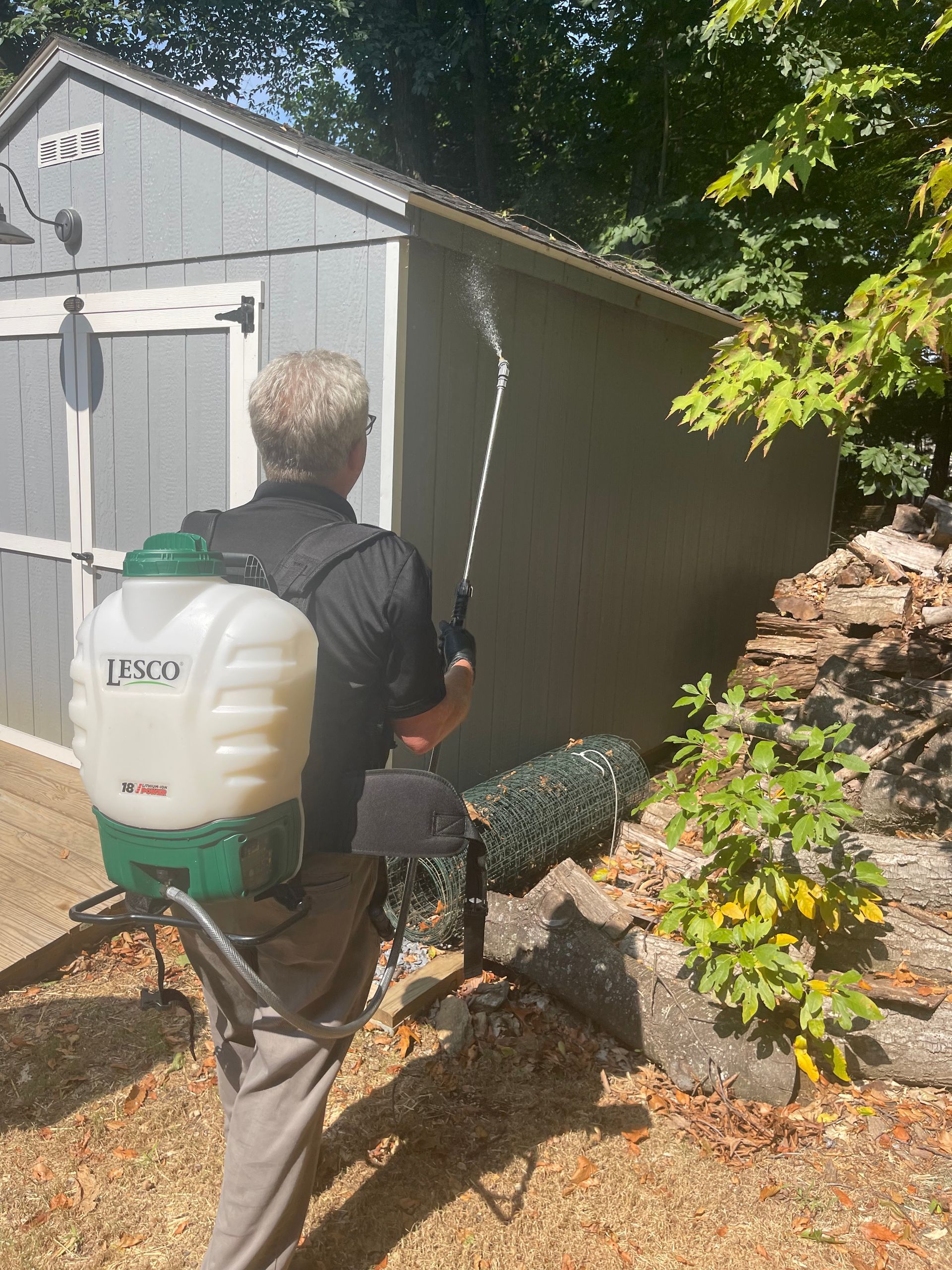 Rob of keystone pest solutions LLC is spraying a shed with a backpack sprayer to kill bugs