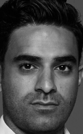 Close-up zwart-witportret van een man die recht in de camera kijkt.