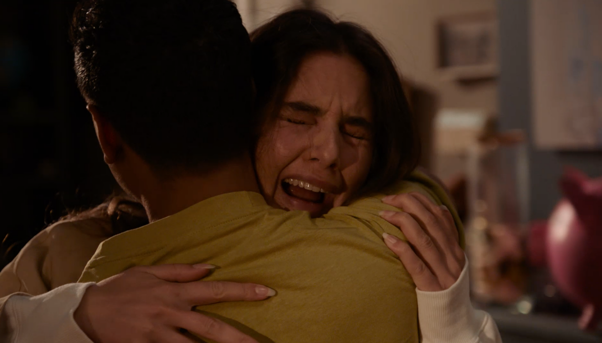 Huilende vrouw omhelst iemand met haar rug naar het beeld toe. Binnen, ze lijkt geëmotioneerd.