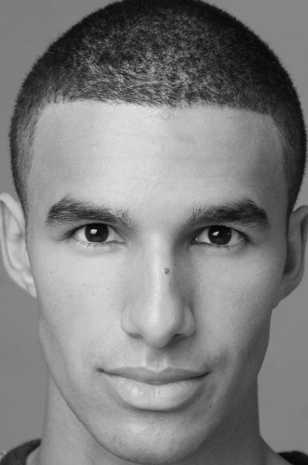 Close-up, zwart-witportret van een man met kort haar en een neutrale uitdrukking.