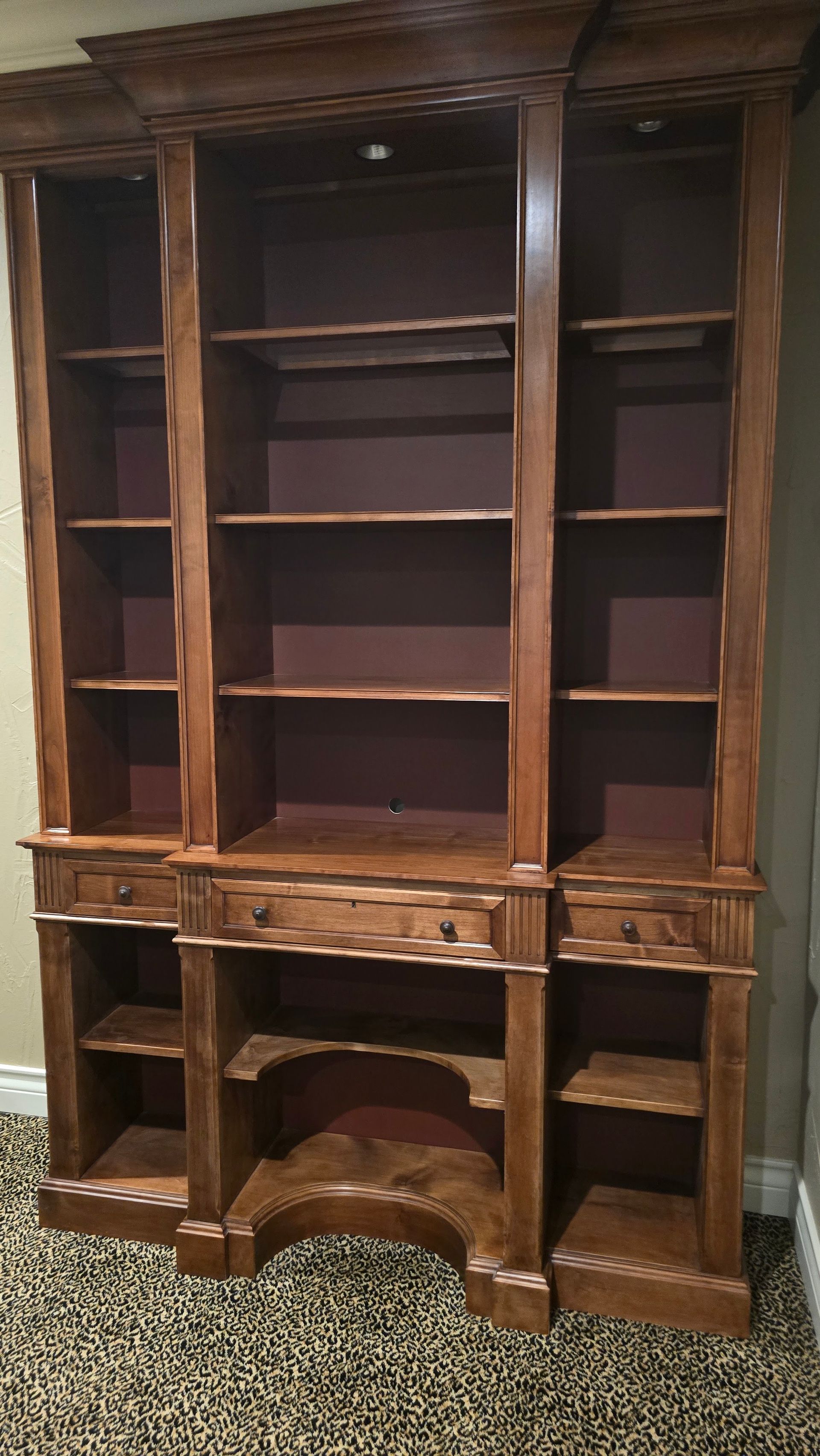 Wooden built-in shelving unit, partially constructed against a white wall; unfinished room with a window.