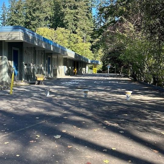 A building with a blue roof is showing the beginning of bollard installation
