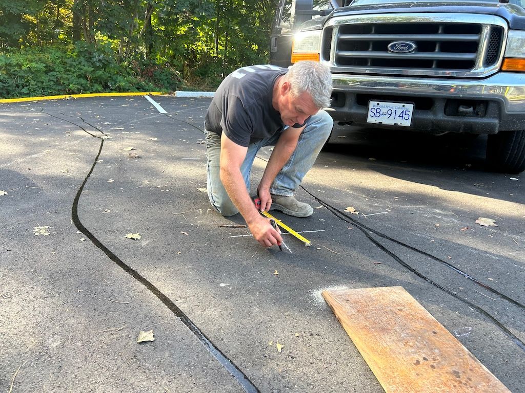A man is measuring bollard positioning n the ground in front of a truck.
